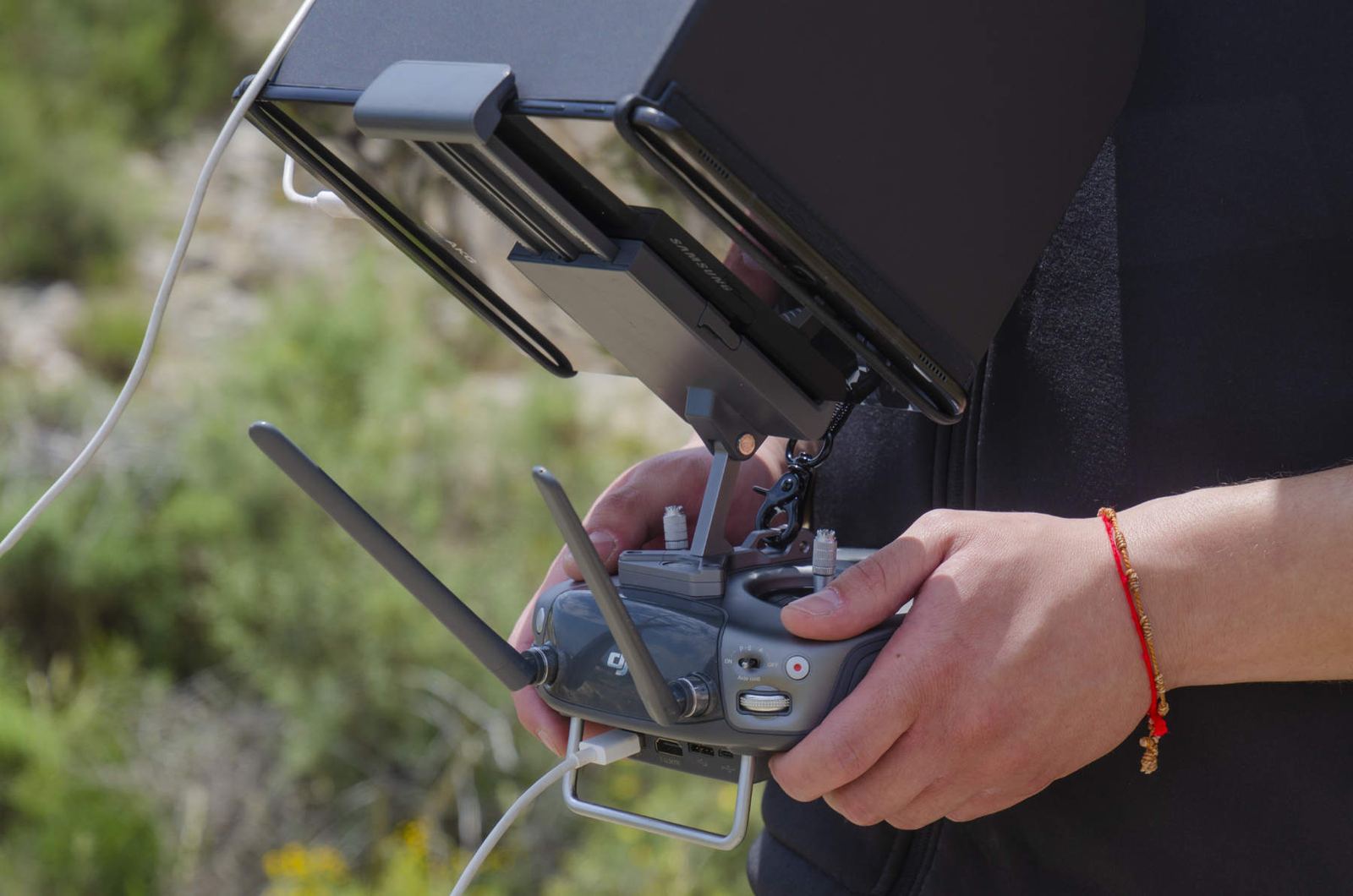 Manos operando la emisora de un dron con la pantalla de vuelo a la vista