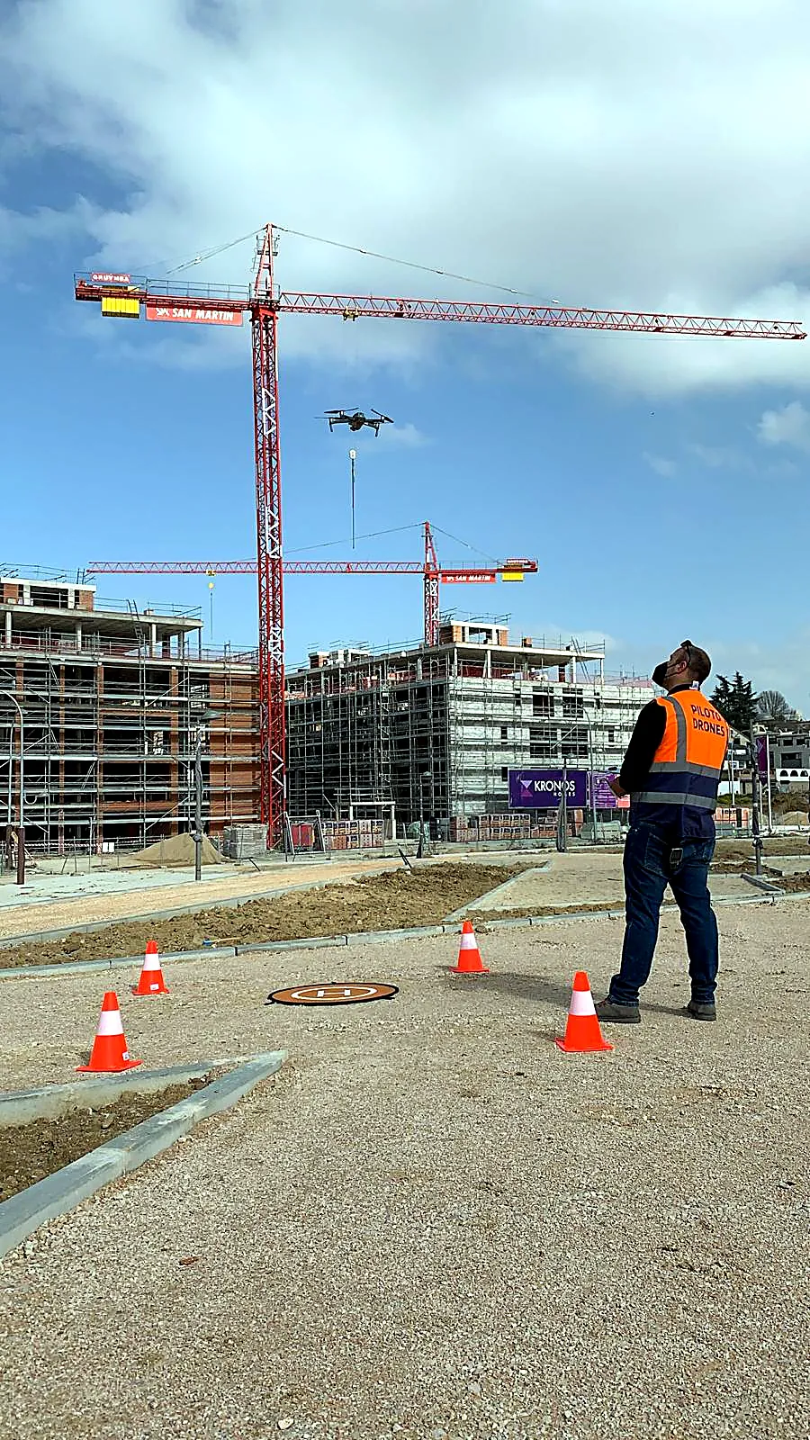 Piloto de drones volando sobre una obra en ejecución con grúas torre